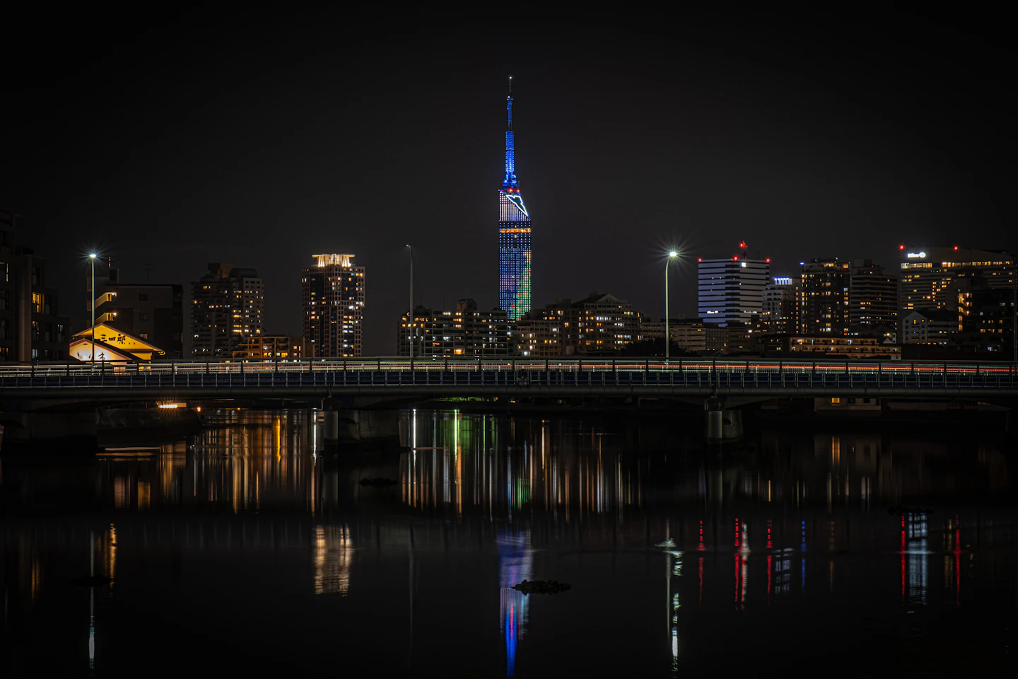 Fukuoka Tower and waterfront buildings reflected in the river at night