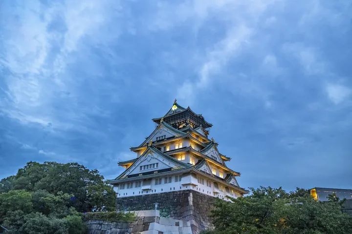 Osaka Castle illuminated beneath a blue evening sky